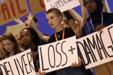 Foto från COP27. Ett antal personer står med plakat i händerna med texten "Deliver Loss + Damage".