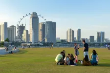 Students on a green space, with skyscrapers in the background. Photo.