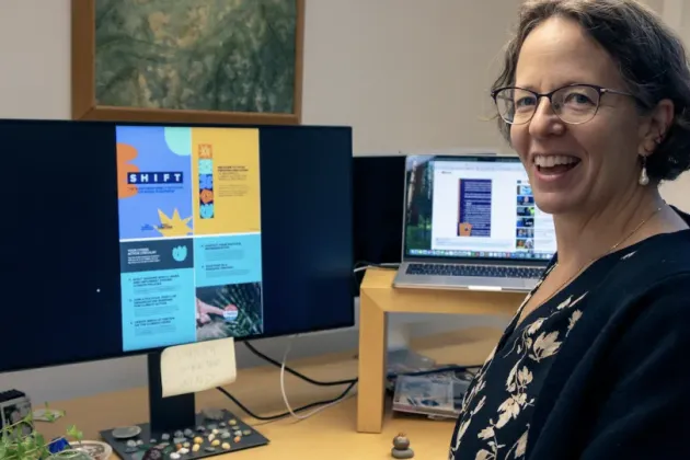 En kvinna, Kimberly Nicholas sittandes framför en datorskärm som visar guiden SHIFT. Bild: Theo Hagman-Rogowski.