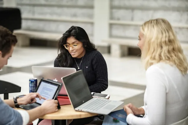 Studenter sitter runt ett bord med sina laptops