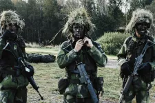 Tre värnpliktiga personer har militärkläder och utrustning på sig. Foto.