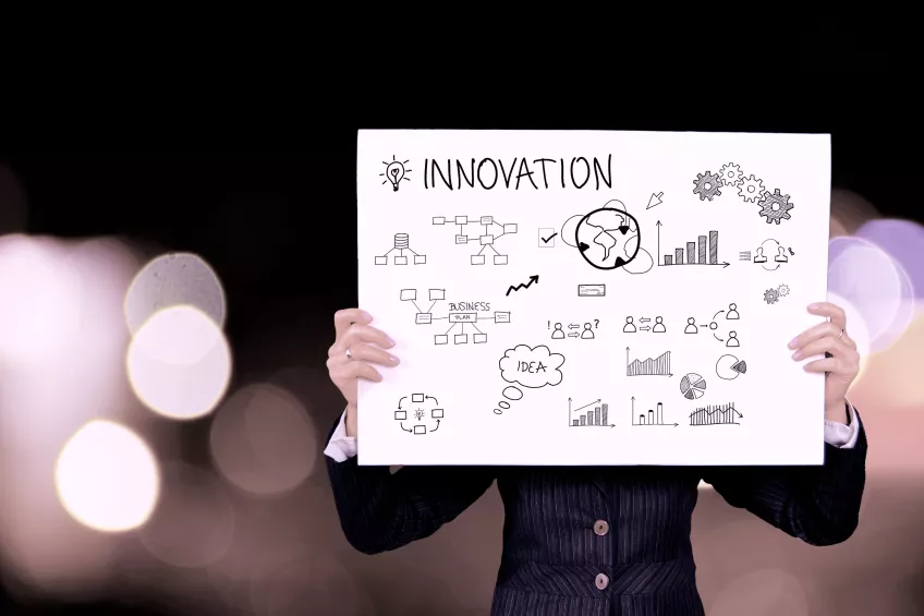 En person håller ett papper med ordet innovation. Foto.
